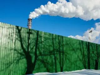 Green fence in front of chimneys. Photographer: Andrey Rudakov/Bloomberg